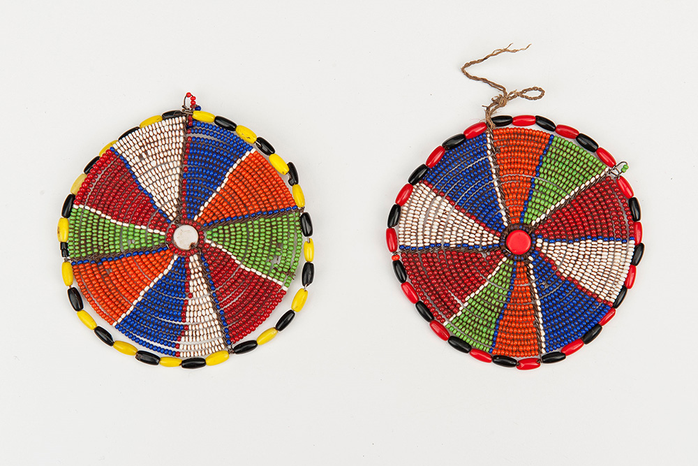 Two flat discs made of beads.  Each disc is divided into slice-like segments of different colors, and bordered with two alternating colored beads.